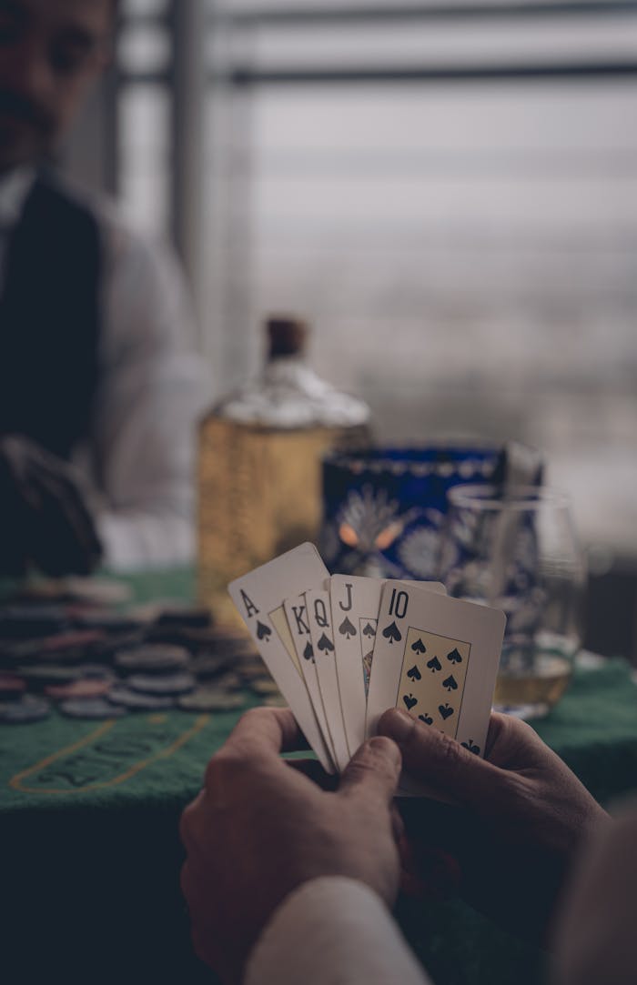 gallery-6 Close-up of spades royal flush in poker game, focus on cards and blurred background setting.