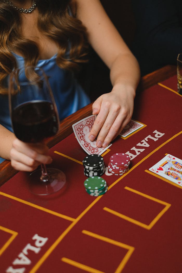 services-03 A woman holding cards and a wine glass at a casino, playing poker.